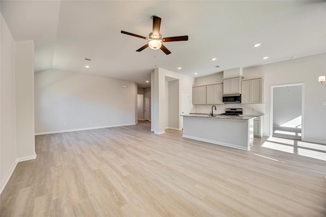 unfurnished living room featuring ceiling fan, vaulted ceiling, sink, and light wood-type flooring