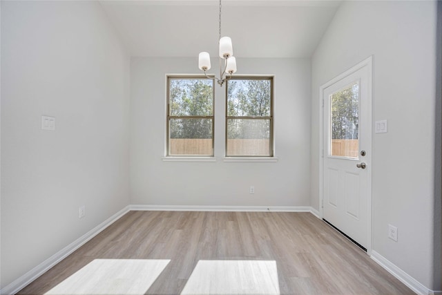 unfurnished dining area with vaulted ceiling, a chandelier, and light hardwood / wood-style flooring