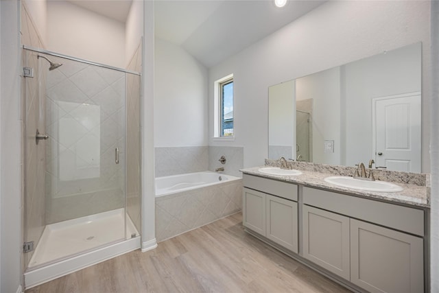 bathroom with wood-type flooring, shower with separate bathtub, vaulted ceiling, and vanity