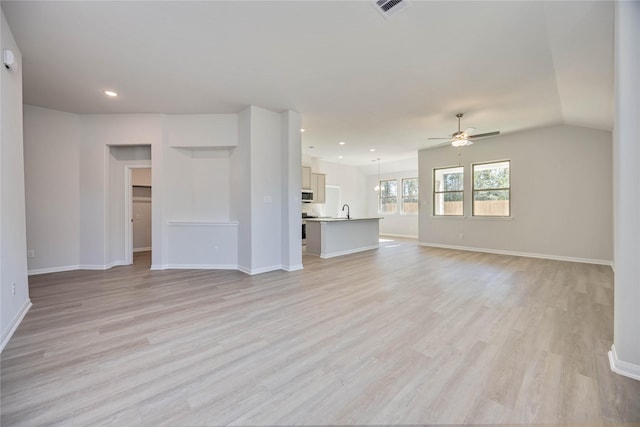 unfurnished living room with ceiling fan, sink, and light wood-type flooring