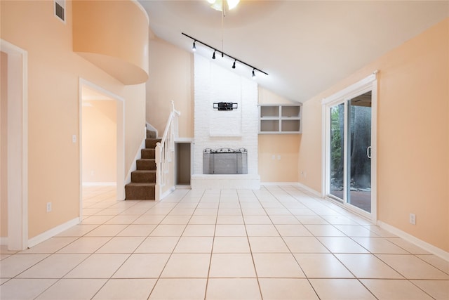 unfurnished living room featuring light tile patterned flooring, a large fireplace, lofted ceiling, and track lighting