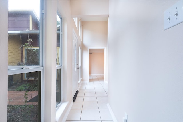 hallway with light tile patterned flooring and a high ceiling