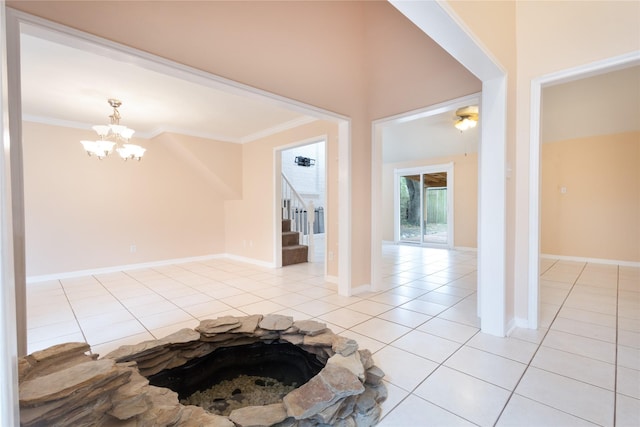 tiled entrance foyer featuring ornamental molding and a chandelier