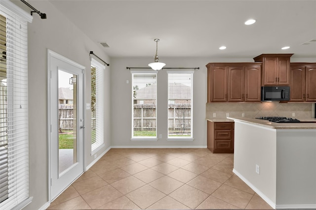 kitchen featuring hanging light fixtures, decorative backsplash, black appliances, and light tile patterned floors