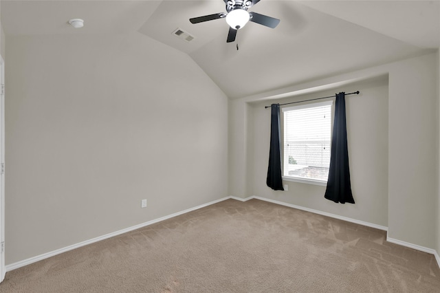 empty room with ceiling fan, vaulted ceiling, and light carpet