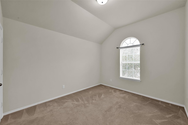 carpeted spare room featuring vaulted ceiling