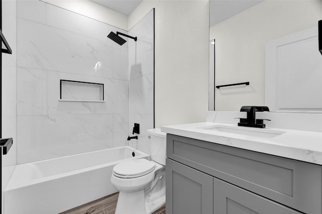 full bathroom with hardwood / wood-style flooring, vanity, toilet, and tiled shower / bath combo