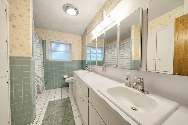 bathroom with curtained shower, tile walls, vanity, toilet, and tile patterned floors