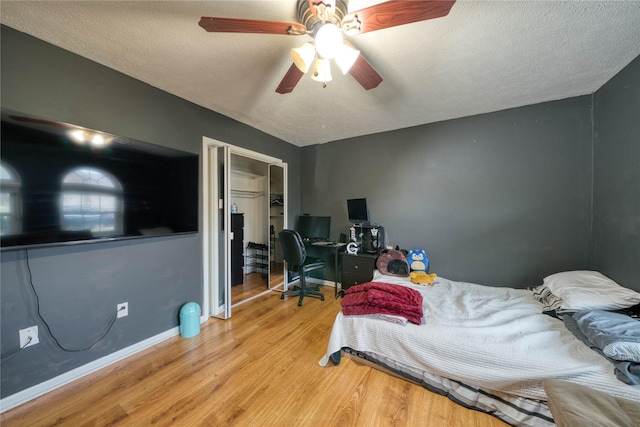 bedroom with ceiling fan, a closet, light hardwood / wood-style flooring, and a textured ceiling