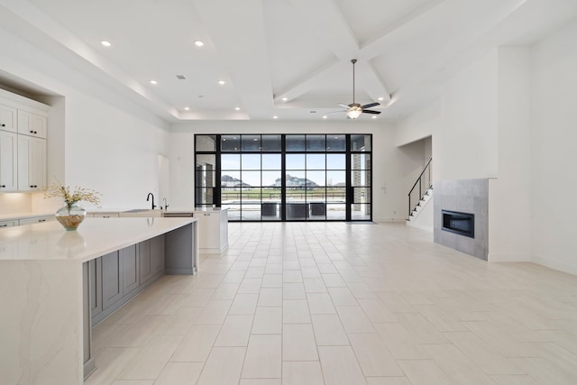 kitchen featuring a tile fireplace, beamed ceiling, white cabinetry, coffered ceiling, and a spacious island