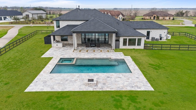 back of property with a yard, a pool with hot tub, and a patio area