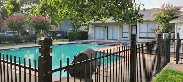 community pool with a patio area and fence