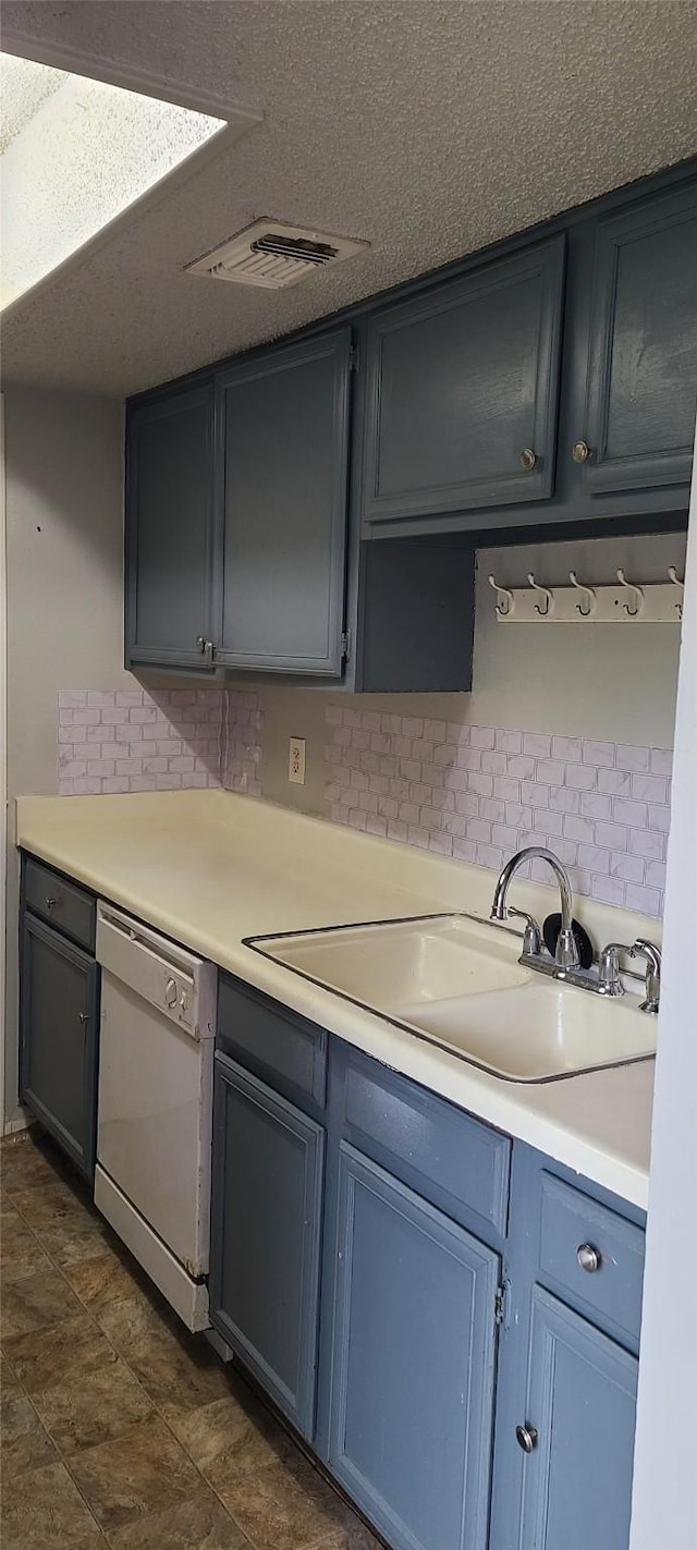 kitchen with visible vents, white dishwasher, a sink, decorative backsplash, and light countertops