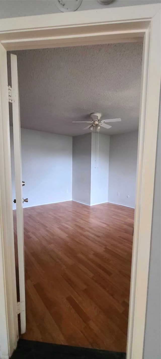 empty room with a textured ceiling, wood finished floors, and ceiling fan