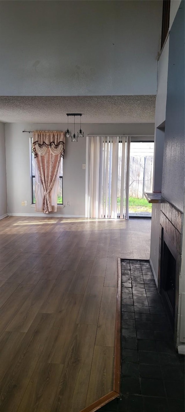 unfurnished living room with dark wood-style floors, a tile fireplace, and a textured ceiling