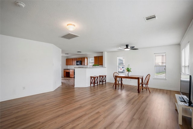 living room with ceiling fan, a textured ceiling, and light wood-type flooring