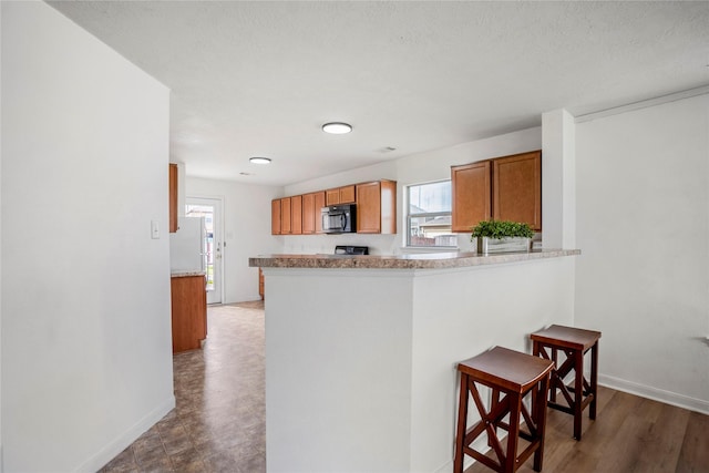 kitchen featuring a kitchen breakfast bar, kitchen peninsula, and a textured ceiling