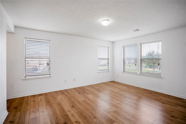 spare room with a textured ceiling and light hardwood / wood-style floors