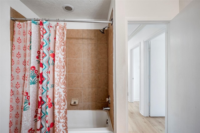 bathroom featuring hardwood / wood-style floors, shower / tub combo, and a textured ceiling