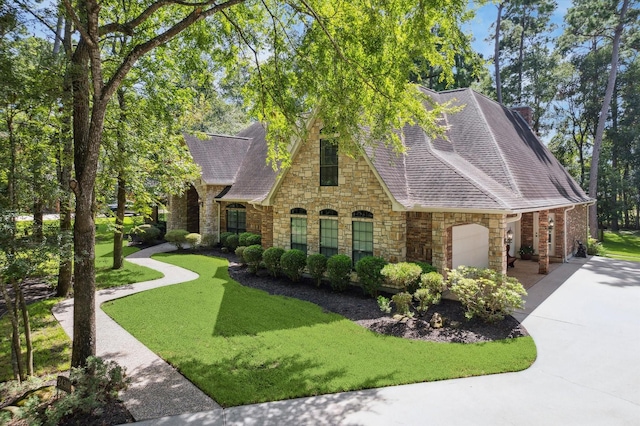 view of front of house with a chimney, a shingled roof, a front yard, a garage, and driveway