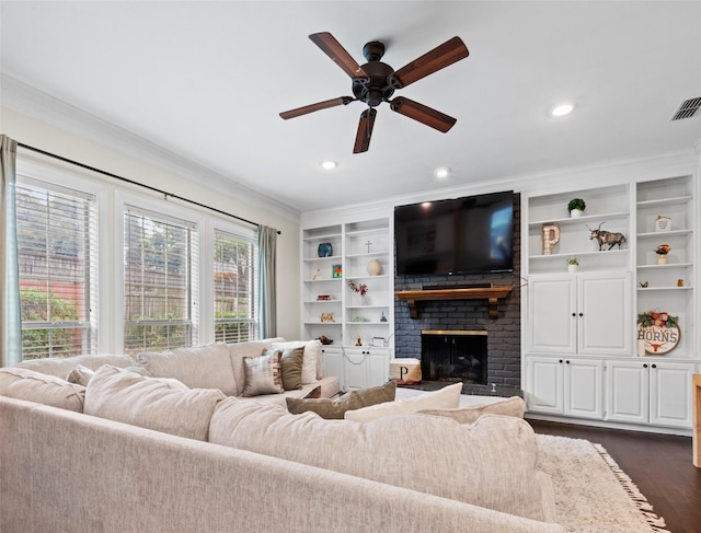 living room with built in features, ceiling fan, dark hardwood / wood-style floors, a fireplace, and ornamental molding