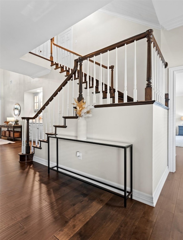 staircase with crown molding, vaulted ceiling, and hardwood / wood-style floors