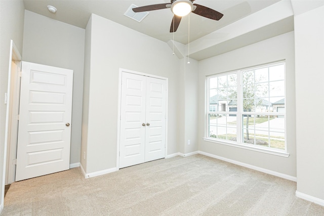 unfurnished bedroom featuring ceiling fan, light colored carpet, and a closet