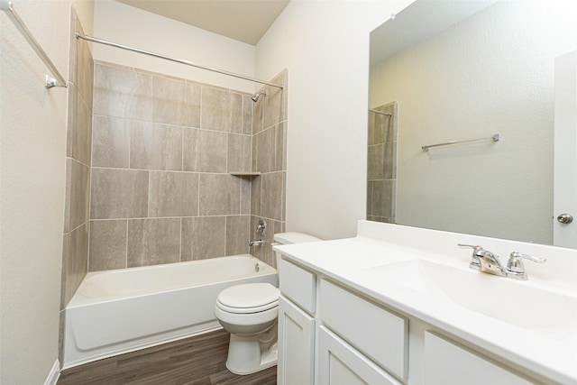 full bathroom with vanity, hardwood / wood-style floors, tiled shower / bath, and toilet