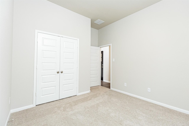 unfurnished bedroom featuring light colored carpet and a closet