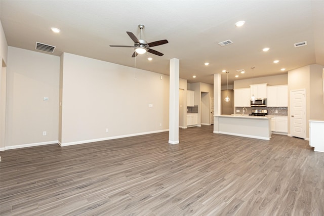 unfurnished living room featuring sink, ceiling fan, and light wood-type flooring