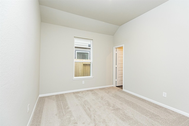 carpeted spare room with lofted ceiling