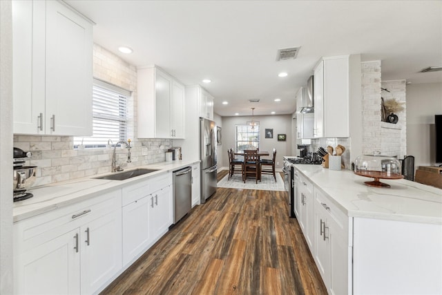 kitchen with sink, appliances with stainless steel finishes, white cabinetry, light stone countertops, and dark hardwood / wood-style flooring