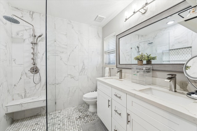 bathroom with tiled shower, vanity, toilet, and tile walls