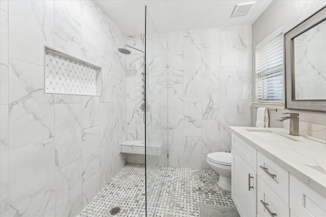 bathroom featuring vanity, toilet, and a tile shower