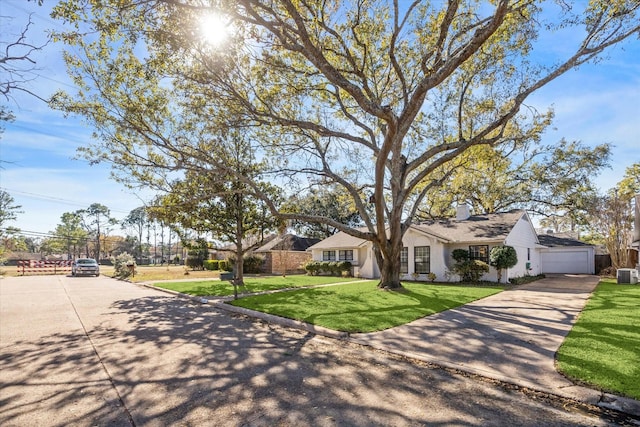 ranch-style house featuring a garage, central air condition unit, and a front lawn