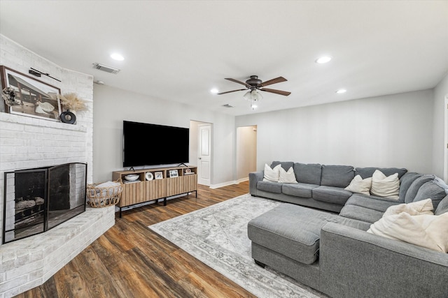 living room featuring ceiling fan, a fireplace, and dark hardwood / wood-style flooring