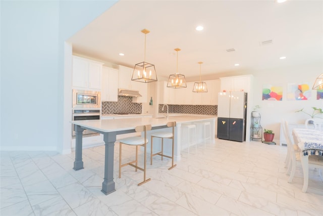 kitchen with a breakfast bar area, tasteful backsplash, decorative light fixtures, stainless steel appliances, and white cabinets