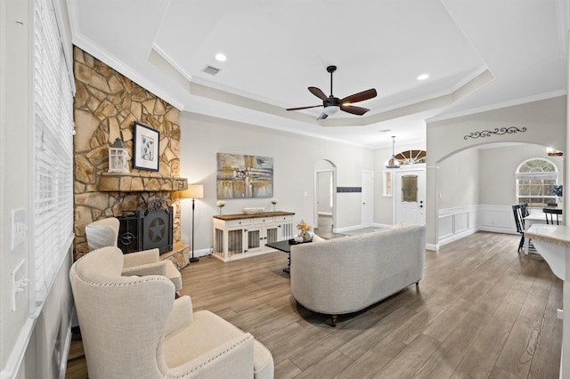 living room featuring hardwood / wood-style flooring, ornamental molding, a fireplace, and a raised ceiling