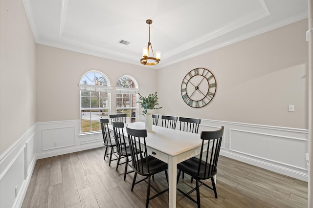 dining room featuring a tray ceiling, wood-type flooring, and a chandelier