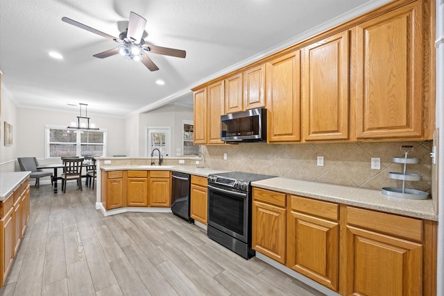 kitchen with pendant lighting, sink, appliances with stainless steel finishes, ornamental molding, and kitchen peninsula