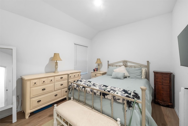 bedroom with vaulted ceiling and light hardwood / wood-style flooring