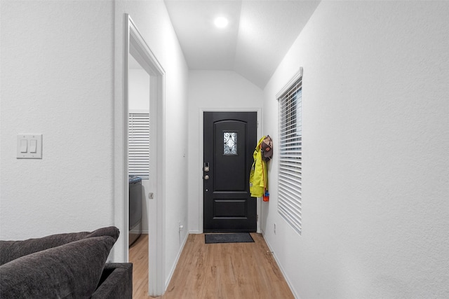 doorway to outside with lofted ceiling and light hardwood / wood-style floors