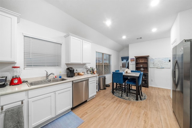 kitchen with white cabinetry, lofted ceiling, sink, light hardwood / wood-style floors, and stainless steel appliances