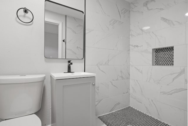 bathroom featuring vanity, toilet, and a tile shower