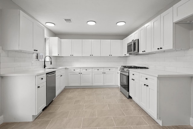 kitchen featuring stainless steel appliances, sink, white cabinets, and decorative backsplash