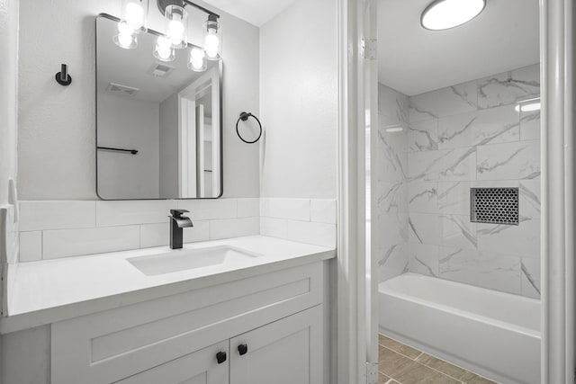 bathroom with tasteful backsplash, vanity, and tiled shower / bath combo