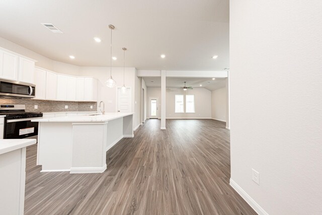 3013 Plains Cir, Brookshire, TX 77423 - kitchen featuring backsplash, light wood-type flooring, light countertops, appliances with stainless steel finishes, and white cabinetry
