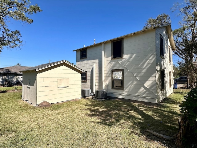 back of house with cooling unit and a lawn