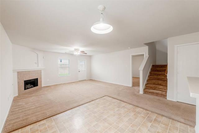 unfurnished living room with light carpet, a tile fireplace, and ceiling fan