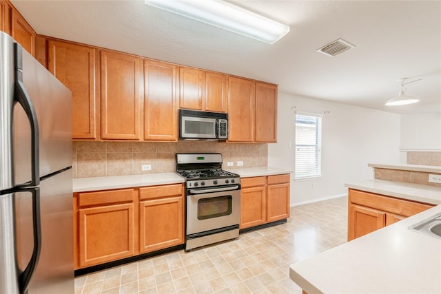 kitchen featuring stainless steel appliances, hanging light fixtures, and decorative backsplash